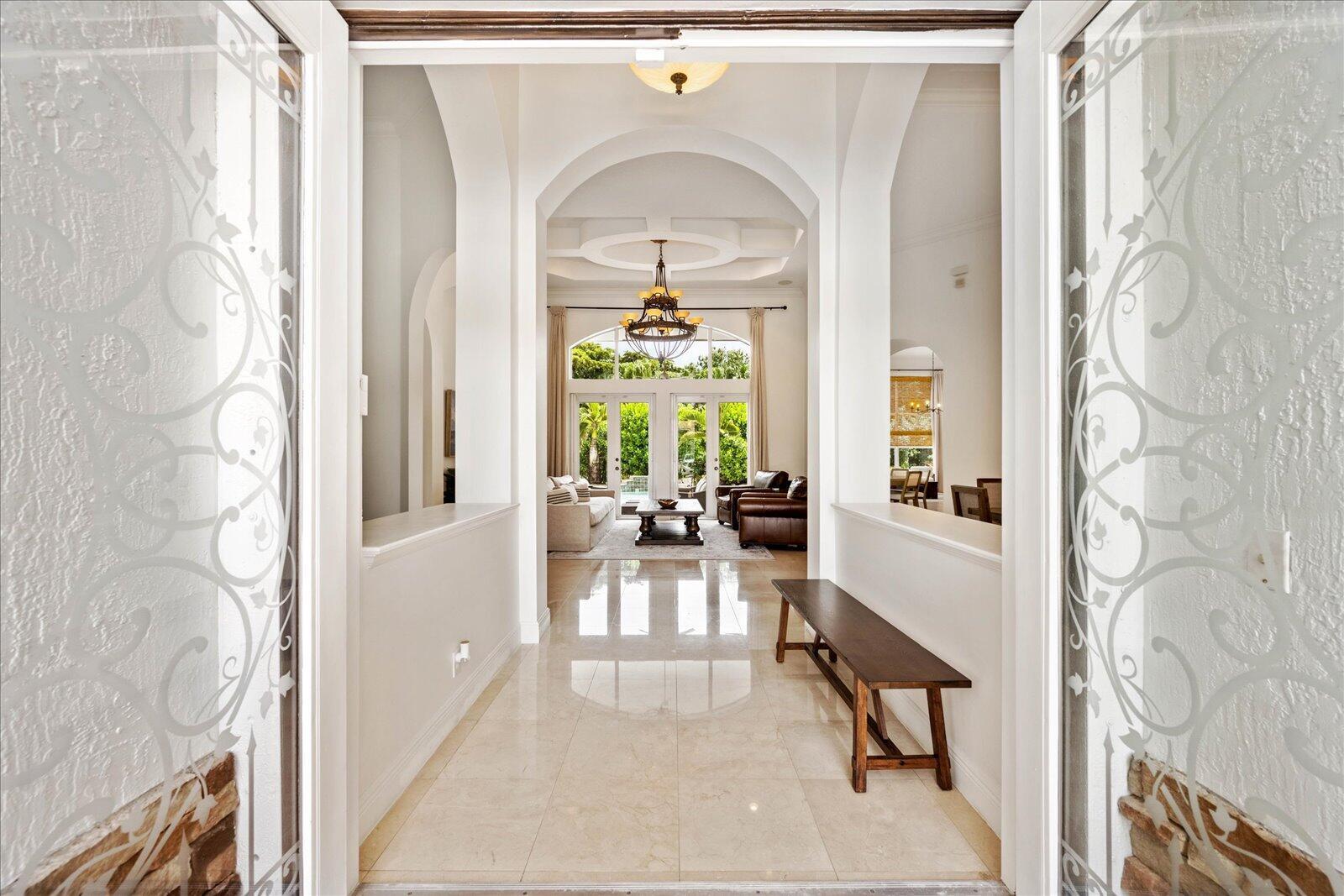 A bright entryway with tile floors leads through arched doorways to a living room beyond — 12486 Equine Lane, Wellington FL 33414, WELLINGTON, FL