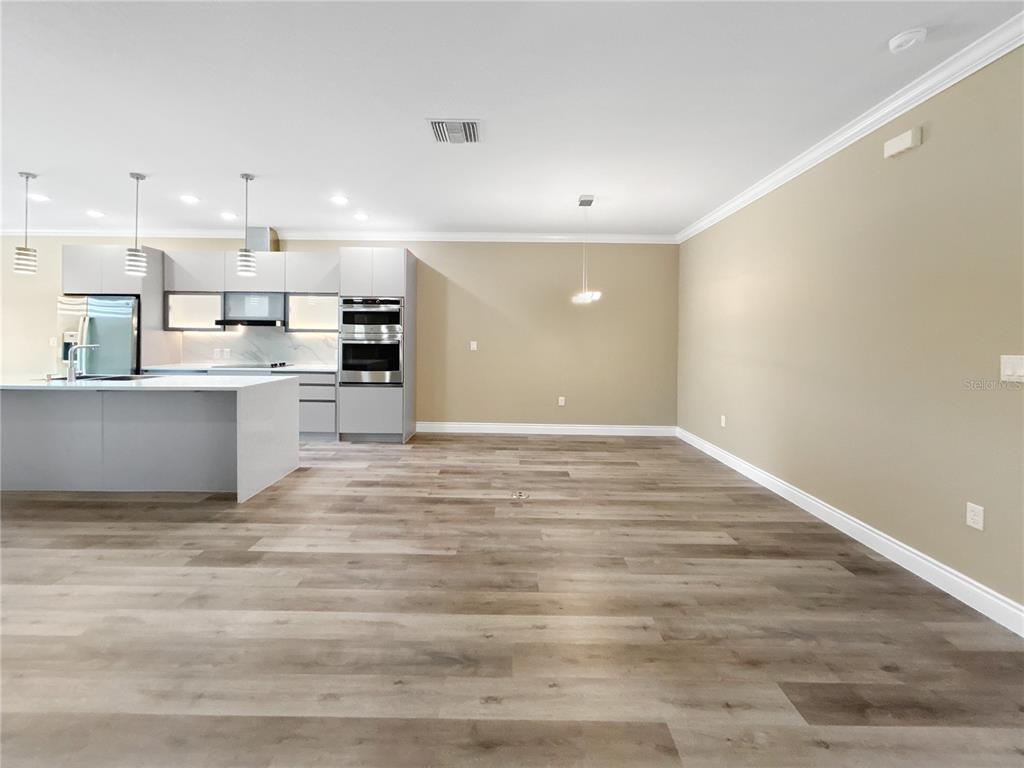 A modern kitchen with light gray cabinetry, a white island, and wood-look flooring — 1839 BRENTWOOD COURT, DAVENPORT, FL