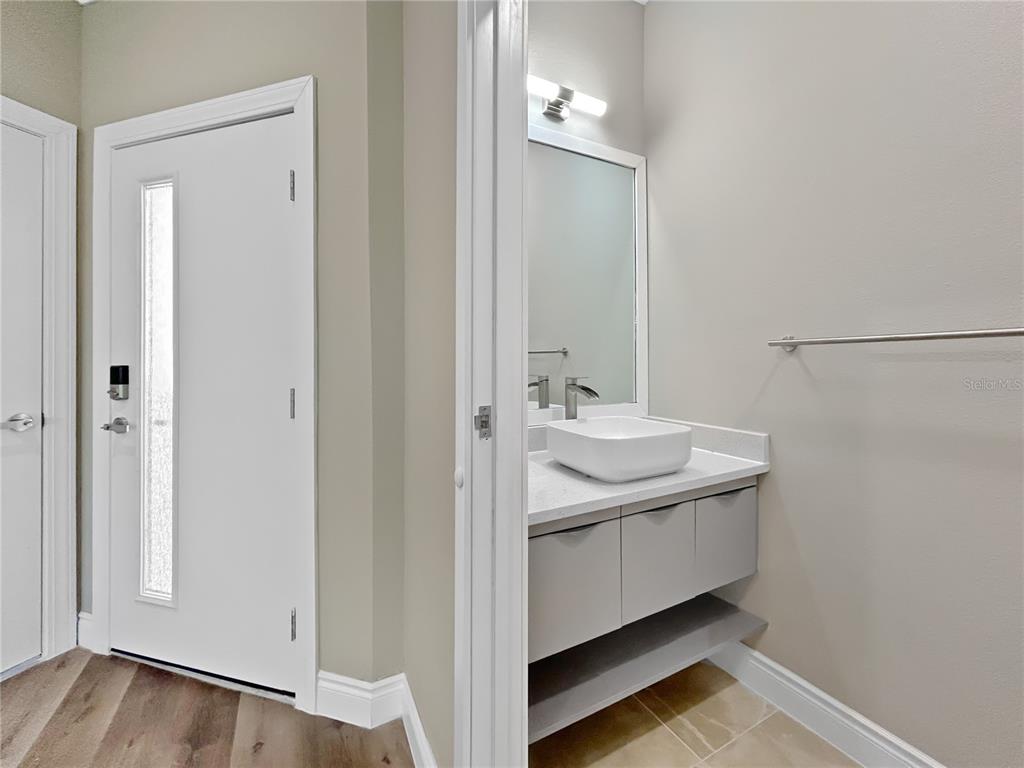 A modern bathroom features a vessel sink, floating vanity, and a mirror next to a door — 1839 BRENTWOOD COURT, DAVENPORT, FL