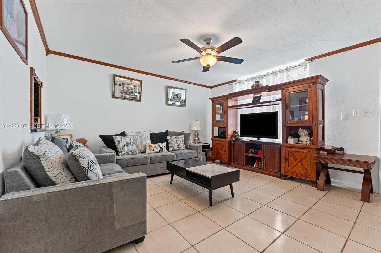 A living room features gray sofas, a wooden entertainment center, and tile flooring — 314 NE 142 St # 16C, Miami FL 33161, MIAMI, FL