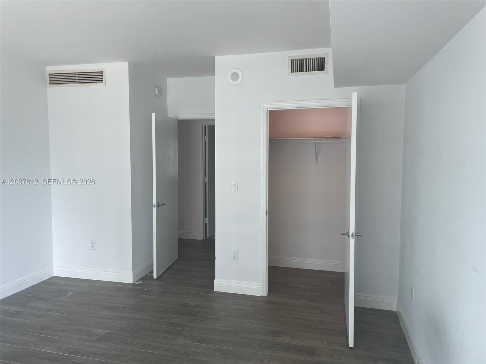 A room with gray wood-look flooring, white walls, two open doorways, and two ceiling vents — 500 Brickell Av # 1906, Miami FL 33131, MIAMI, FL