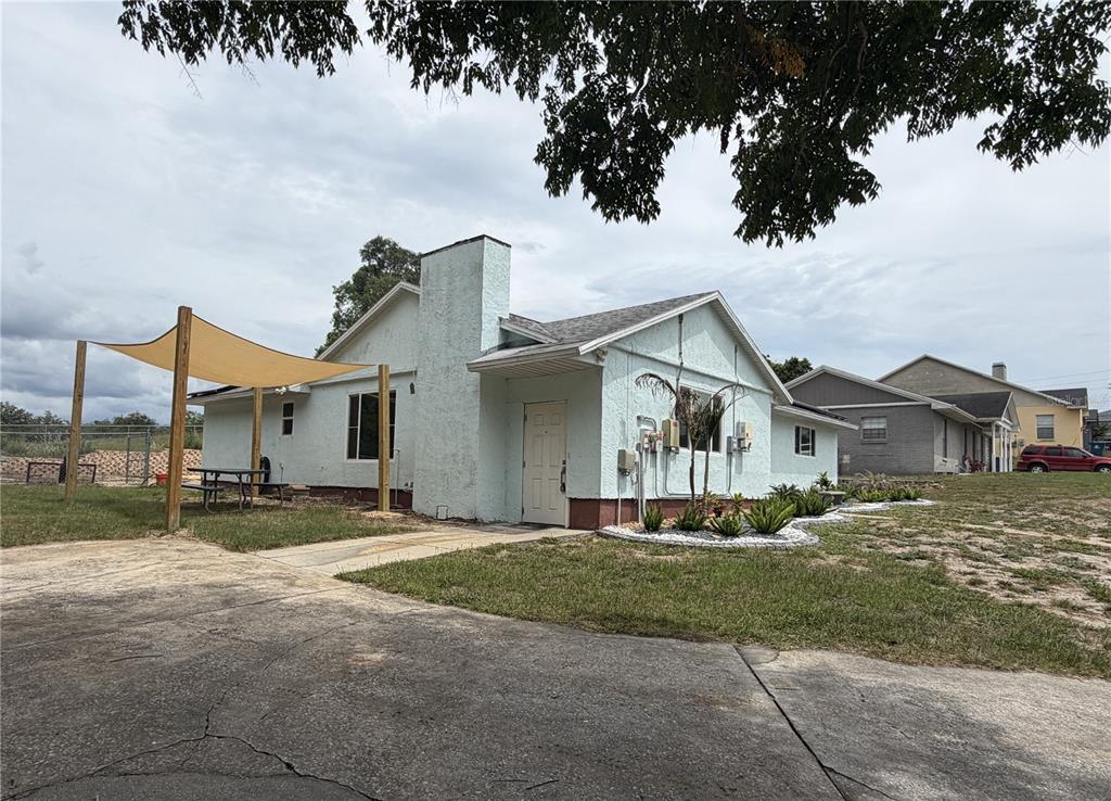 A light blue, single-story house with a chimney, a shade sail, and a concrete driveway — 7 LAGO VISTA COURT, DAVENPORT, FL
