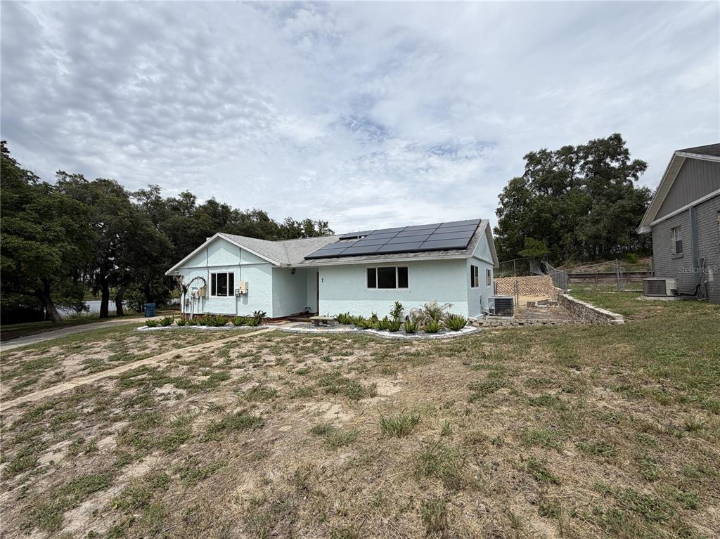 A light blue single-story house with solar panels on the roof and a grassy yard — 7 LAGO VISTA COURT, DAVENPORT, FL