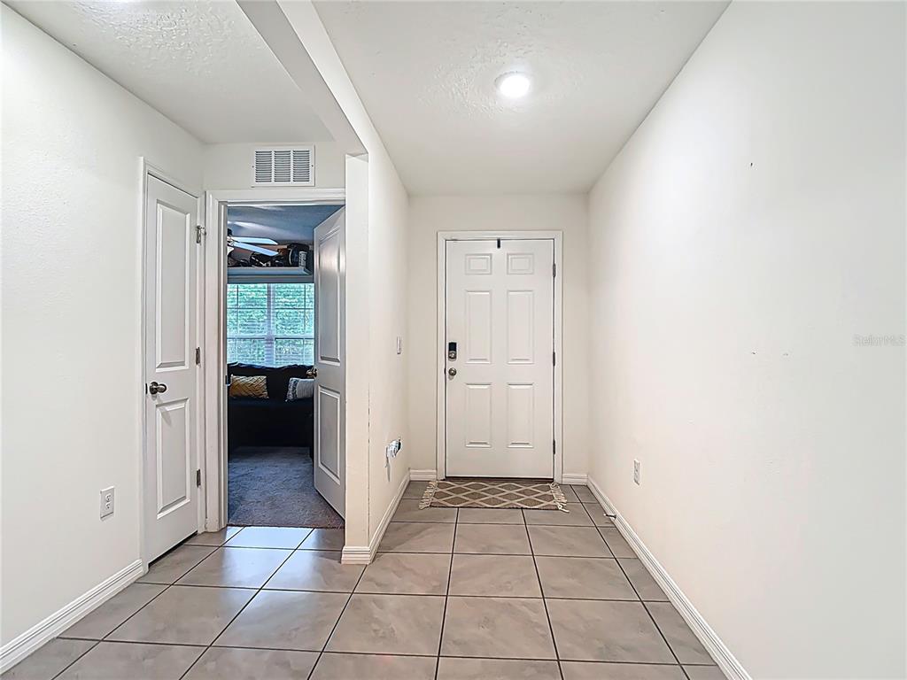 An entryway with tile flooring leads to a front door and an adjacent room — 5274 DIANTHA WAY, BROOKSVILLE, FL