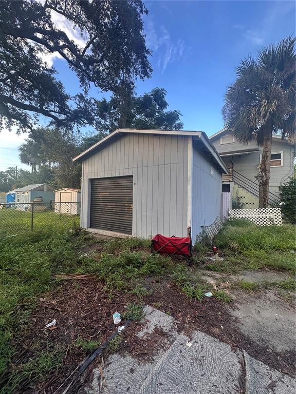 A detached gray shed with a roll-up door sits in a grassy backyard — 821 N RIDGEWOOD AVENUE, DAYTONA BEACH, FL
