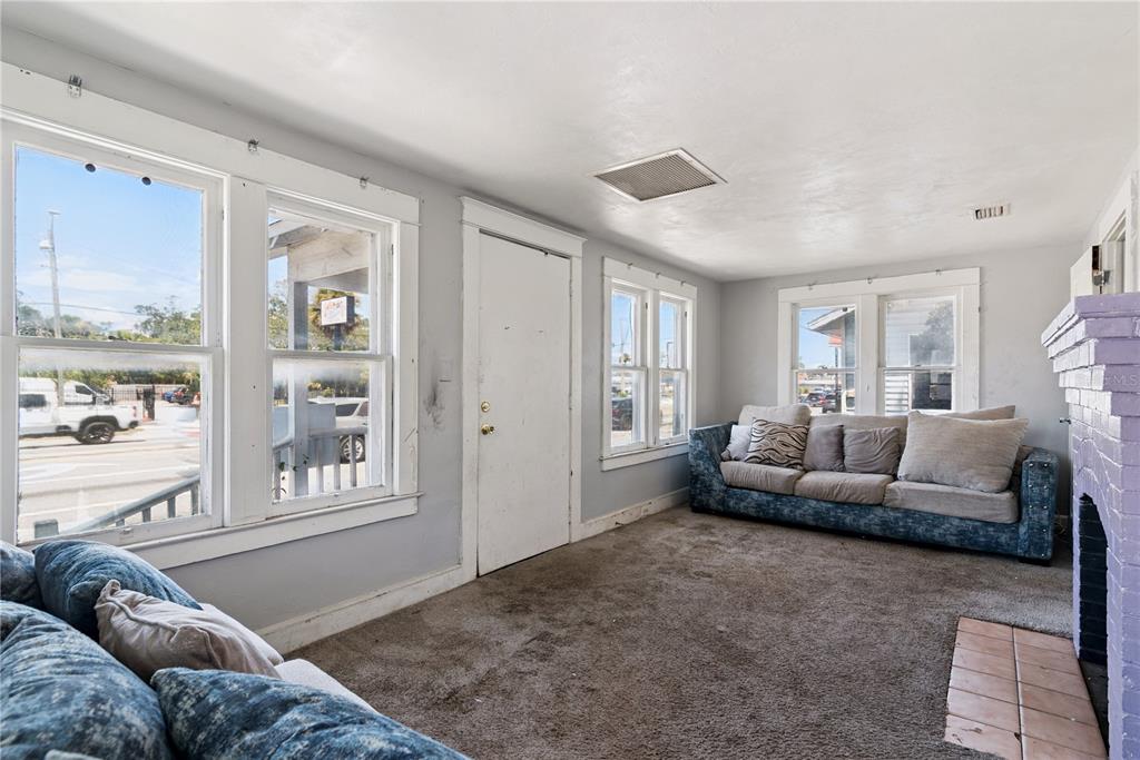 A living room features a purple brick fireplace between two doorways and blue sofas — 821 N RIDGEWOOD AVENUE, DAYTONA BEACH, FL