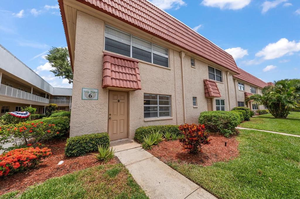 A two-story tan stucco apartment building features a brown tiled roof and a front entrance — 10037 62ND TERRACE N UNIT 1, ST PETERSBURG, FL