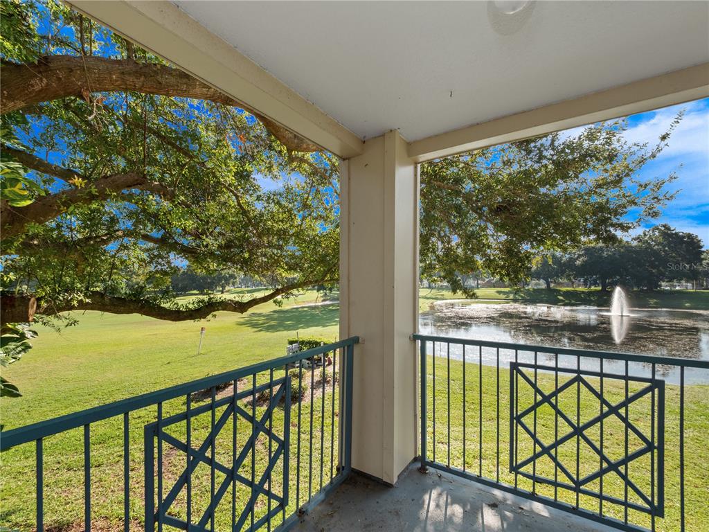 A covered balcony overlooks a grassy golf course and a pond with a fountain — 7210 WESTPOINTE BOULEVARD UNIT 1325, ORLANDO, FL