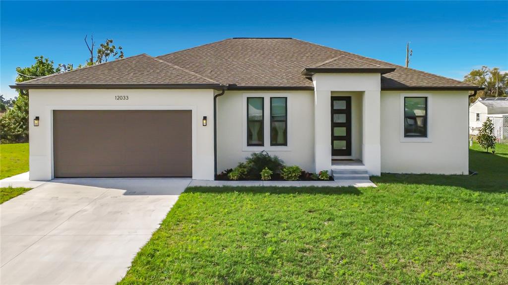 A single-story house with a white stucco exterior, a brown roof, and a two-car garage — 12033 SARTO LANE, NORTH PORT, FL