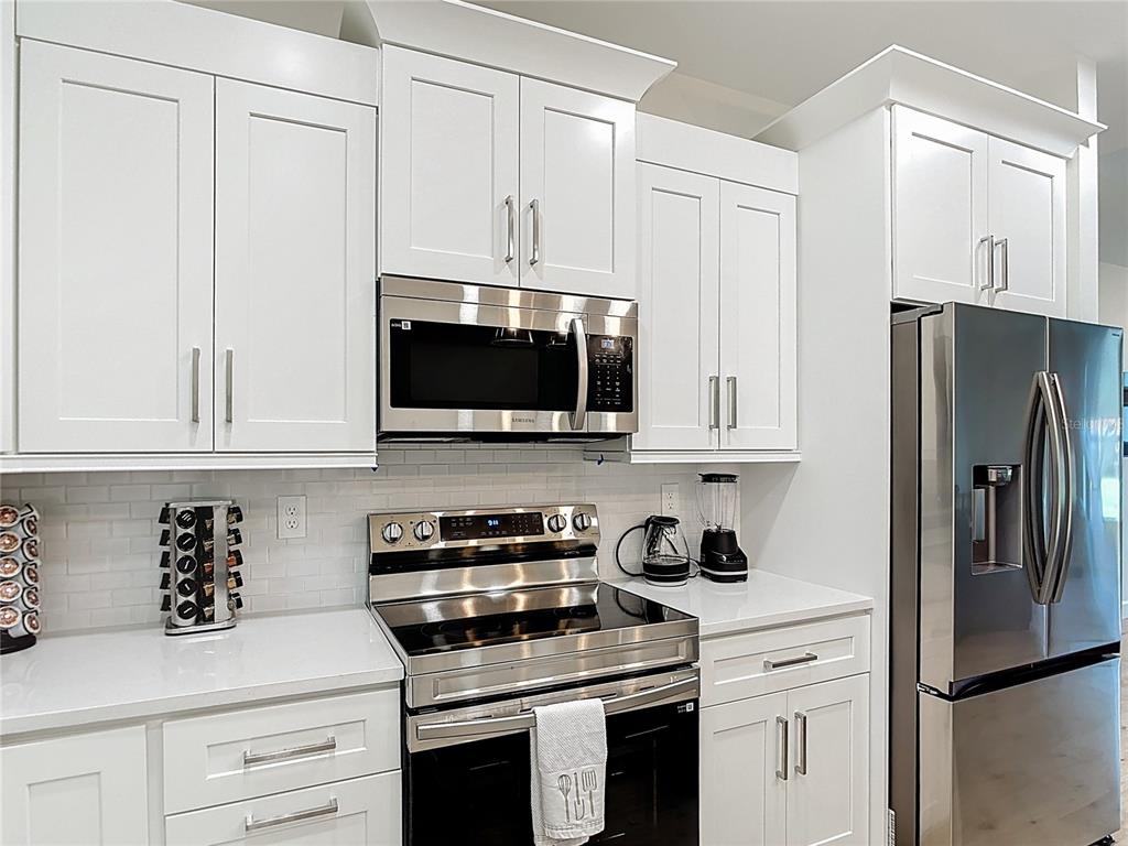 A modern kitchen features white shaker cabinets, stainless steel appliances, and a white subway tile backsplash — 12033 SARTO LANE, NORTH PORT, FL