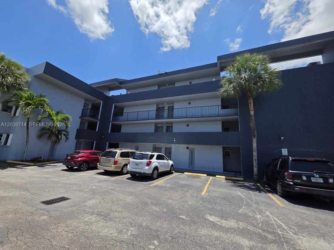 A multi-story apartment building exterior features a parking lot with several parked cars — 8801 W Flagler St # 104, Miami FL 33174, MIAMI, FL