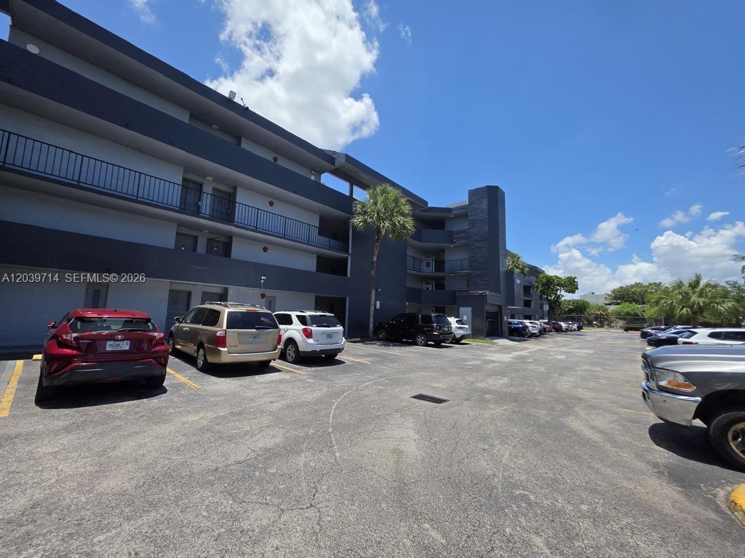 A multi-story apartment building with a parking lot in the foreground under a blue sky — 8801 W Flagler St # 104, Miami FL 33174, MIAMI, FL