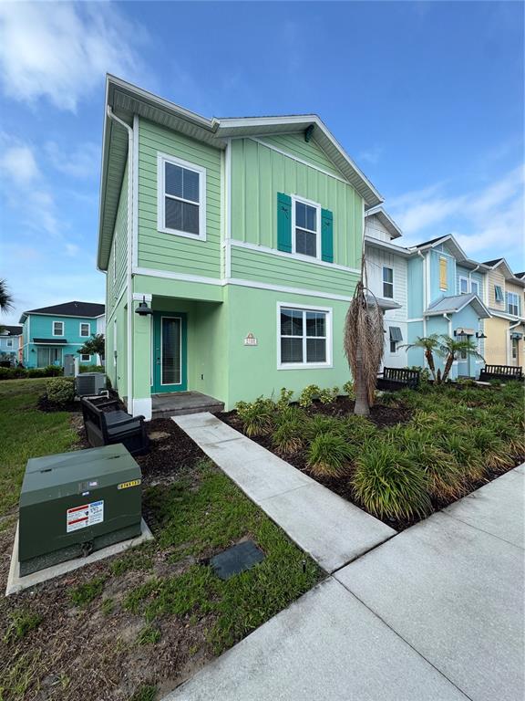 A light green two-story house with a front porch and a concrete walkway — 3188 CARIBBEAN SOUL DRIVE, KISSIMMEE, FL