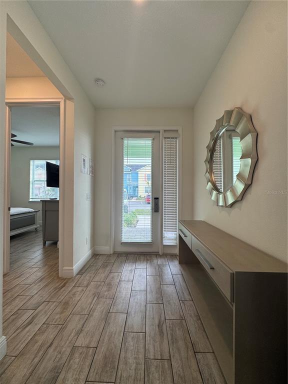 An entryway features wood-look tile flooring, a console table, a round mirror, and a glass-paneled door — 3188 CARIBBEAN SOUL DRIVE, KISSIMMEE, FL