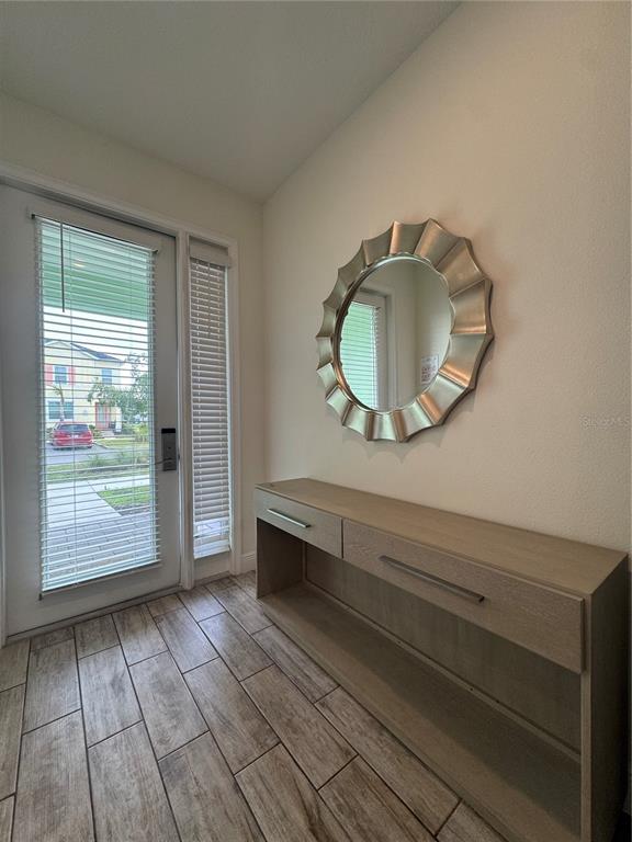 An entryway features a wood-toned console table, a scalloped mirror, and tile flooring — 3188 CARIBBEAN SOUL DRIVE, KISSIMMEE, FL