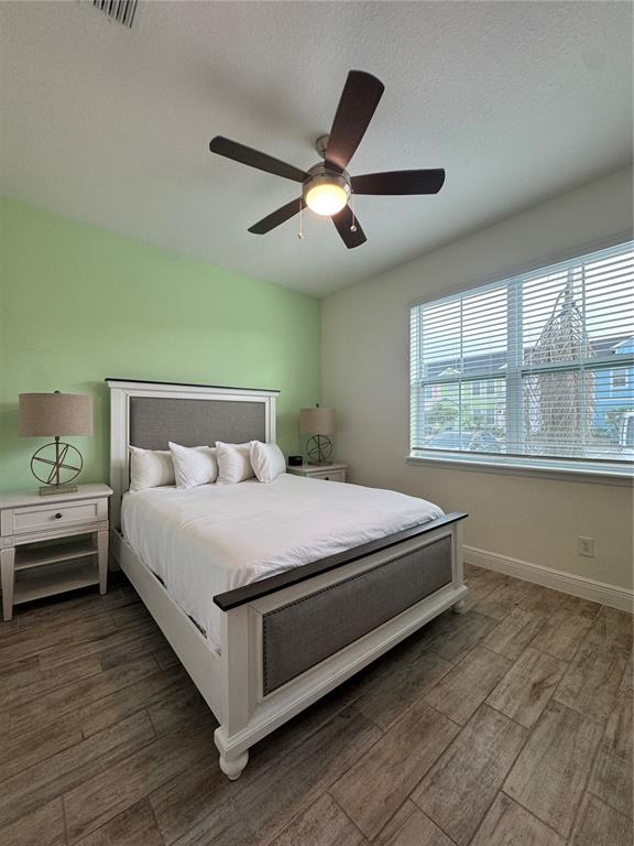 A bedroom features a bed with a gray headboard, light green wall, and wood-look flooring — 3188 CARIBBEAN SOUL DRIVE, KISSIMMEE, FL