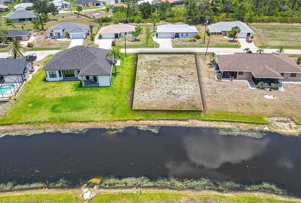 An aerial view shows a vacant rectangular lot situated between two houses near a canal — 168 MARK TWAIN LANE, ROTONDA WEST, FL
