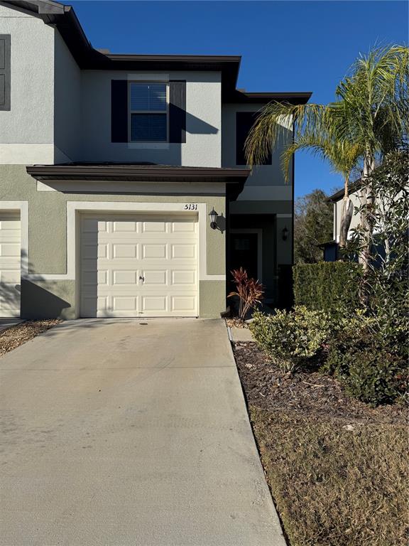 A two-story townhouse exterior features a single-car garage, a concrete driveway, and a palm tree — 5131 FORUM BOULEVARD, HOLIDAY, FL