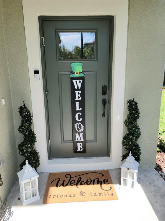 A green front door features a St. Patrick's Day welcome sign, flanked by two spiral topiaries — 5131 FORUM BOULEVARD, HOLIDAY, FL
