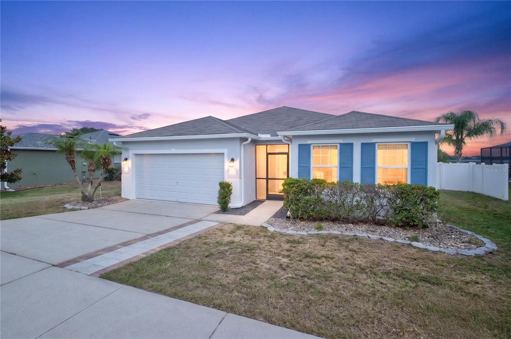 A single-story house with a two-car garage, blue shutters, and a screened front entryway — 713 BLACK EAGLE DRIVE, GROVELAND, FL
