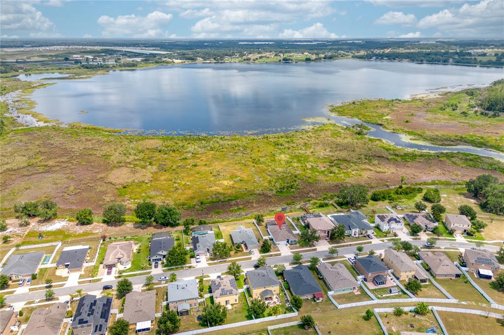 An aerial view shows a suburban neighborhood situated next to a large lake — 713 BLACK EAGLE DRIVE, GROVELAND, FL