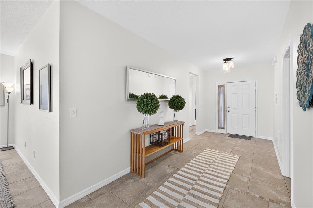 A bright entryway features a tiled floor, a wooden console table, and a white door — 713 BLACK EAGLE DRIVE, GROVELAND, FL