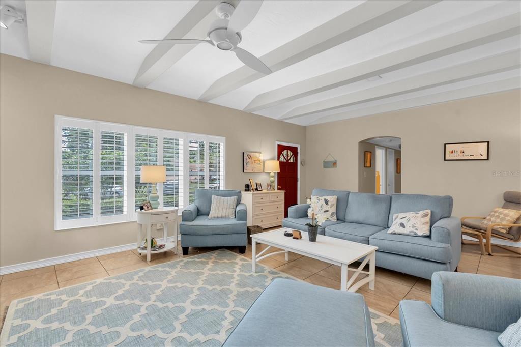 A living room features light blue furniture, a patterned area rug, and white ceiling beams — 6237 13TH AVENUE S, GULFPORT, FL