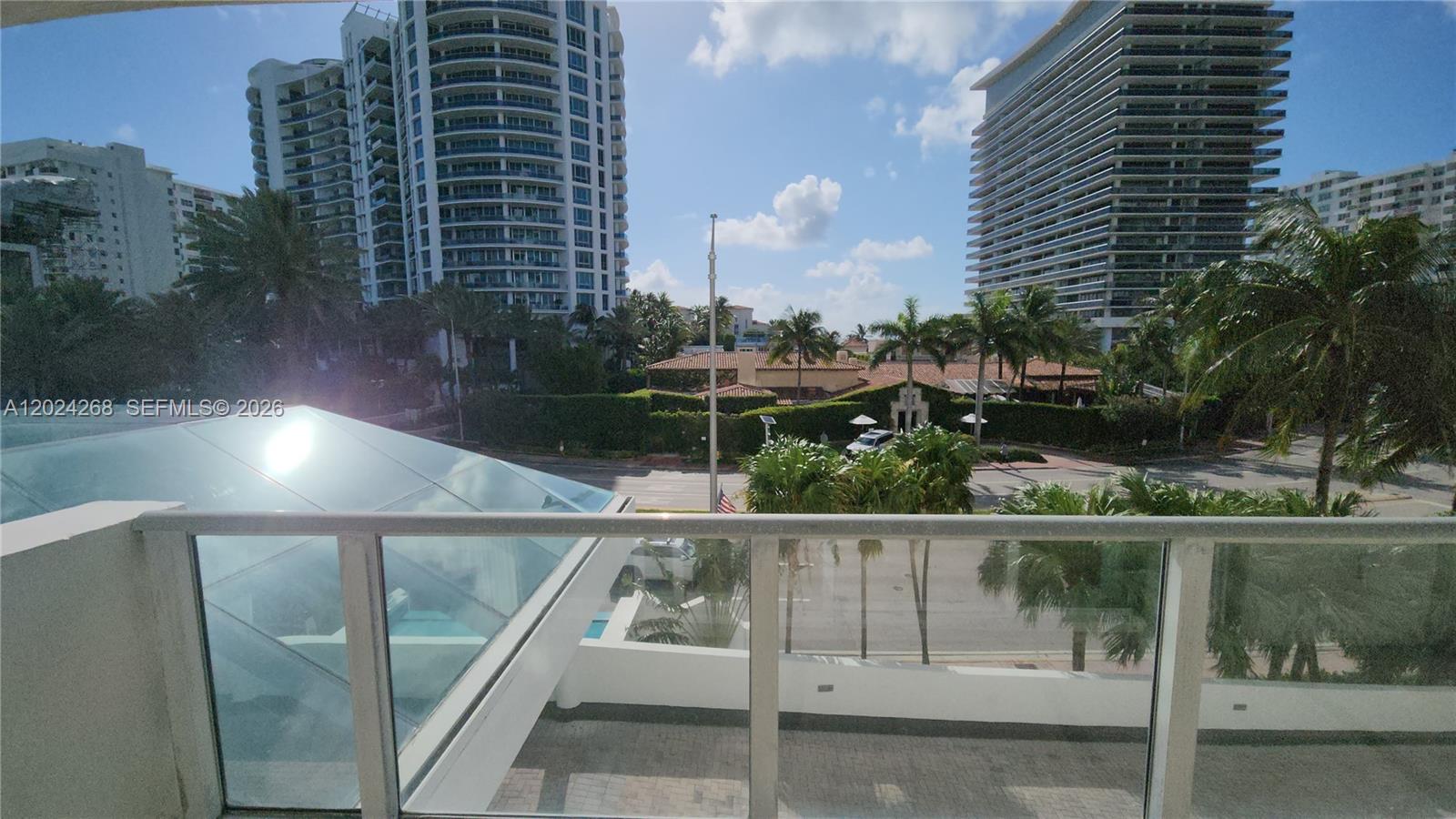 A balcony view overlooks a street, palm trees, and several high-rise buildings — 5900 Collins Ave # 404, Miami Beach FL 33140, MIAMI BEACH, FL