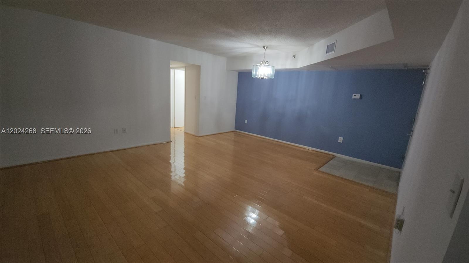 An empty room features light-colored hardwood flooring, white walls, and one blue accent wall — 5900 Collins Ave # 404, Miami Beach FL 33140, MIAMI BEACH, FL