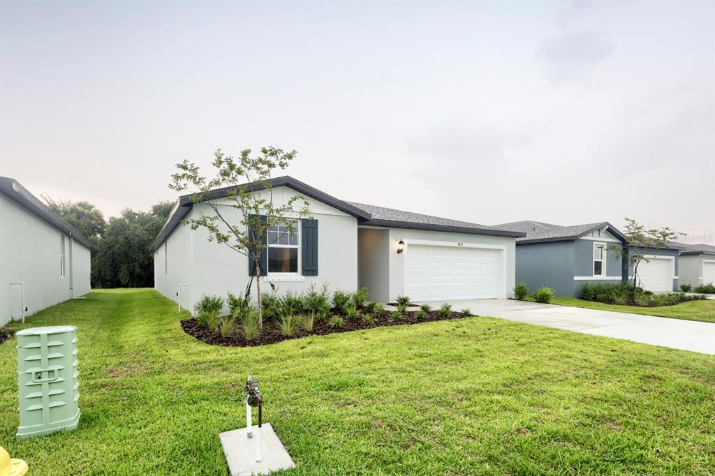 A single-story house with a white garage, gray shutters, and a landscaped front yard — 7637 SATTERFIELD TERRACE, PARRISH, FL