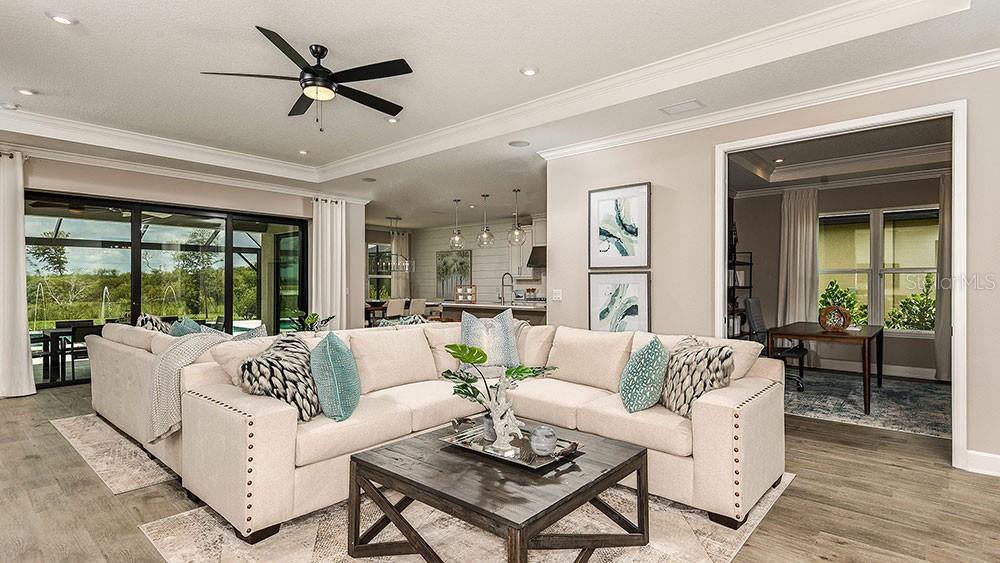 A living room features a beige sectional sofa, a dark wood coffee table, and ceiling fans — 6933 PRAIRIE OAK WAY, NOKOMIS, FL