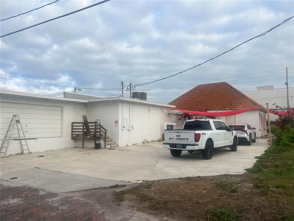 A white building with a garage and a red-tiled roof sits behind a concrete driveway — 856 2ND AVENUE N, ST PETERSBURG, FL