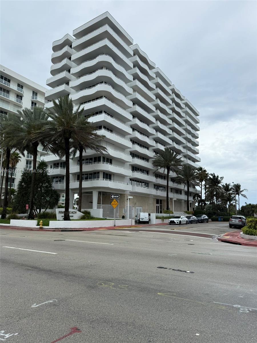 A tall, white multi-story residential building features curved balconies and is surrounded by palm trees — 8911 Collins Ave # 1103, Surfside FL 33154, SURFSIDE, FL