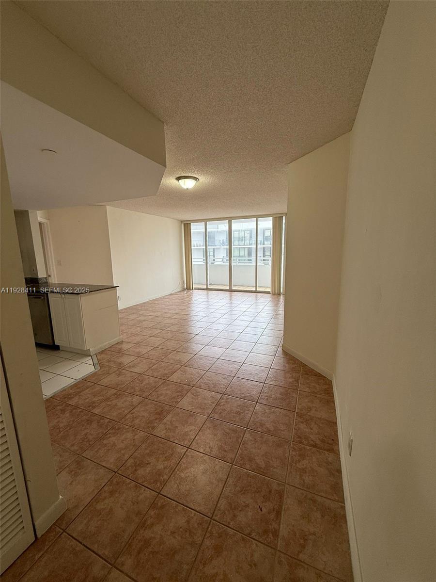 An open-concept living area features beige tile flooring and a sliding glass balcony door — 8911 Collins Ave # 1103, Surfside FL 33154, SURFSIDE, FL