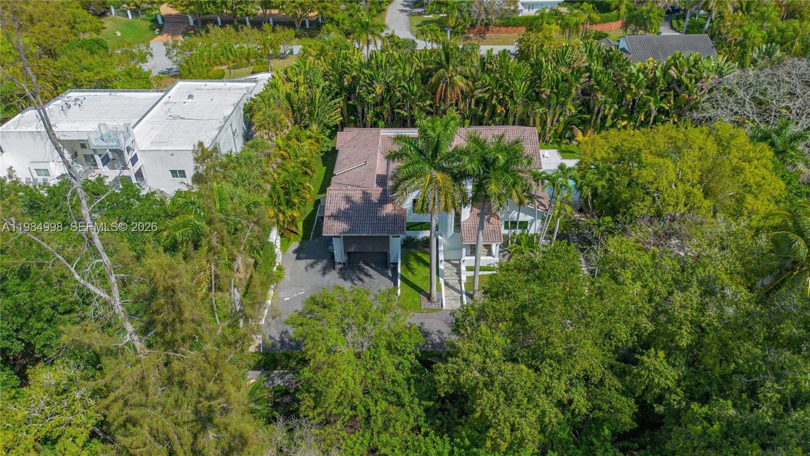 An aerial view shows a two-story house with a tiled roof surrounded by dense trees — 5981 SW 136th St, Pinecrest FL 33156, PINECREST, FL