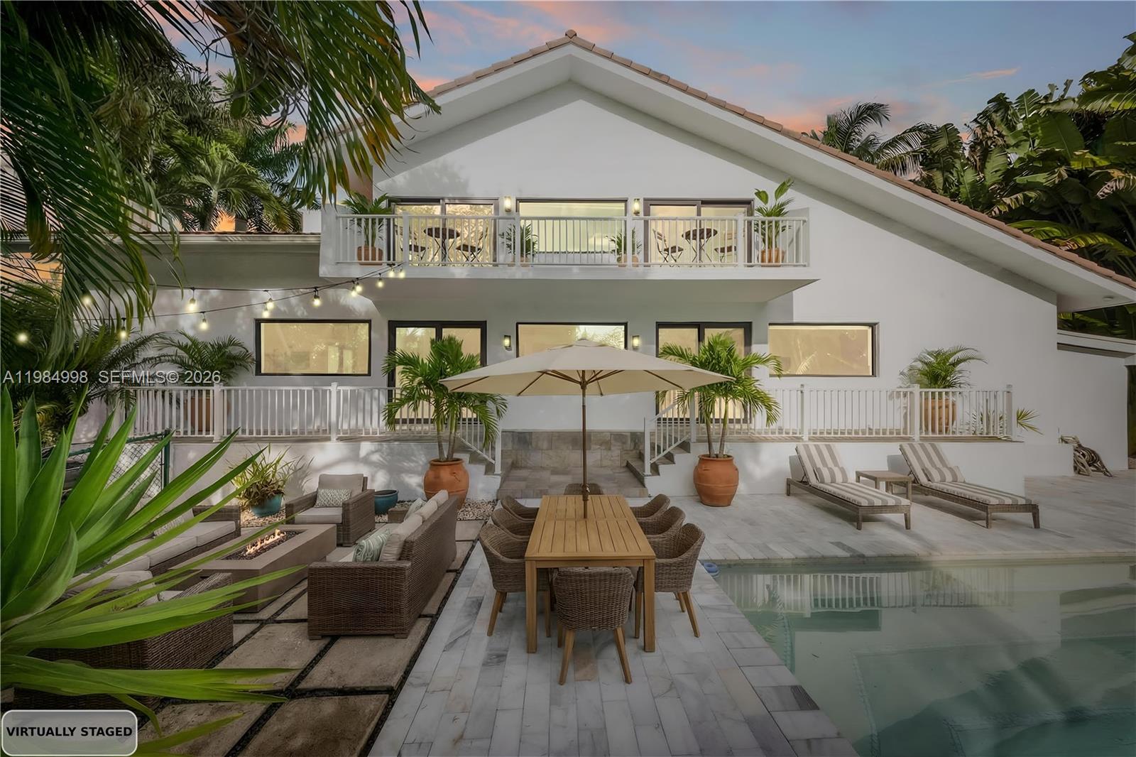 A two-story white house features a backyard patio with a pool, dining area, and lounge — 5981 SW 136th St, Pinecrest FL 33156, PINECREST, FL