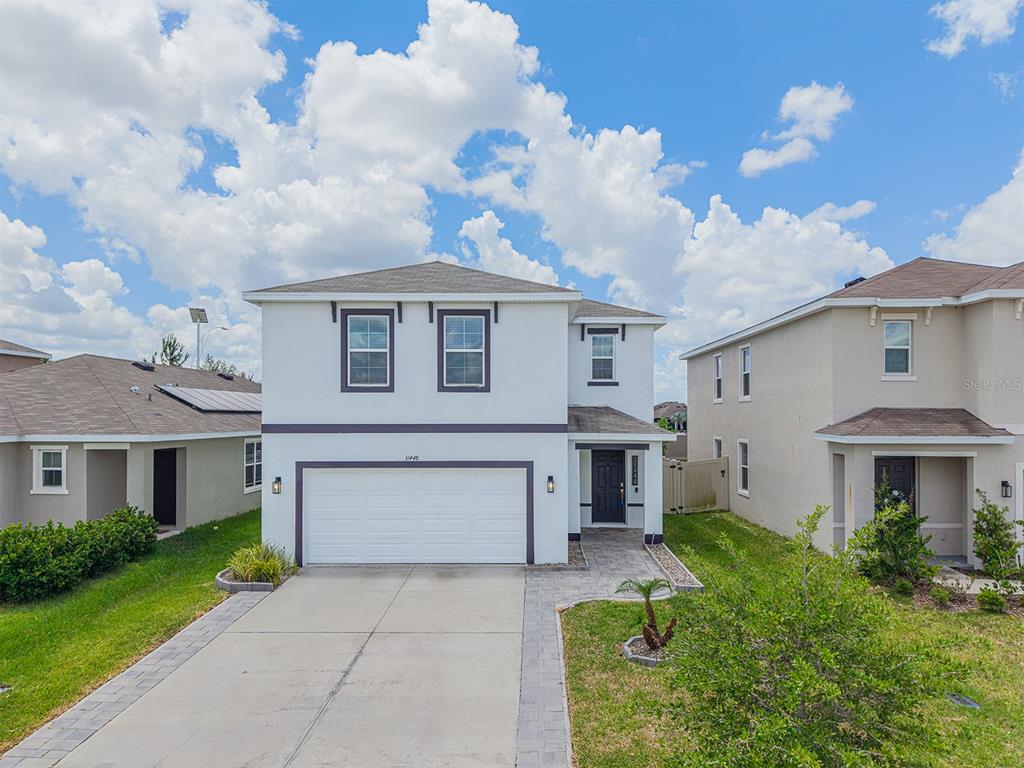 A two-story house with a white exterior, a two-car garage, and a paved driveway — 31448 PENNY SURF LOOP, WESLEY CHAPEL, FL