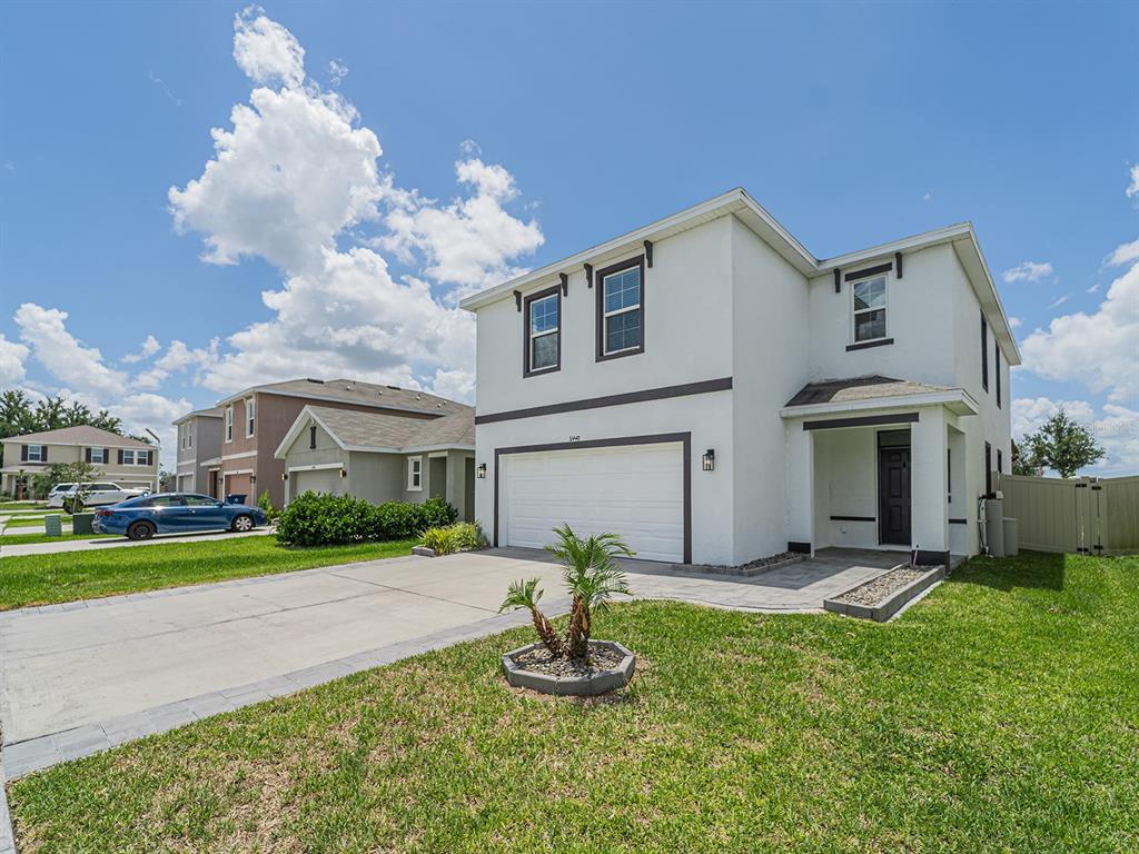 A two-story white stucco house with a two-car garage and a small front lawn — 31448 PENNY SURF LOOP, WESLEY CHAPEL, FL