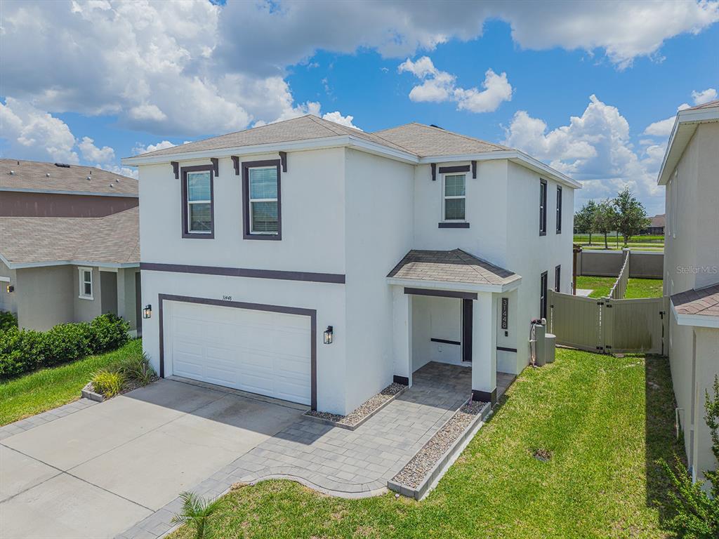 A two-story white stucco house features a two-car garage and a paved walkway entrance — 31448 PENNY SURF LOOP, WESLEY CHAPEL, FL
