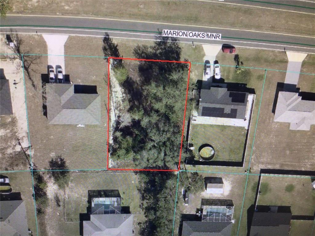 This aerial view shows a vacant, wooded residential lot outlined in red along a road — 0 MARION OAKS MANOR, OCALA, FL