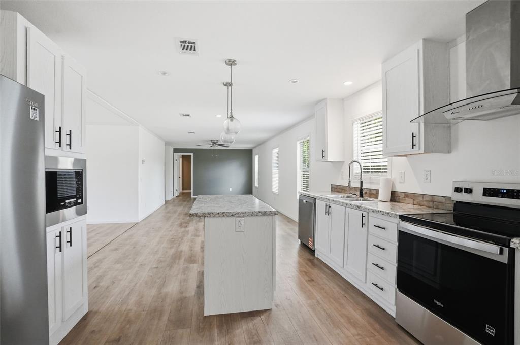 A modern kitchen features white cabinetry, stainless steel appliances, and a central island — 9533 ROUND LAKE DRIVE, WEEKI WACHEE, FL