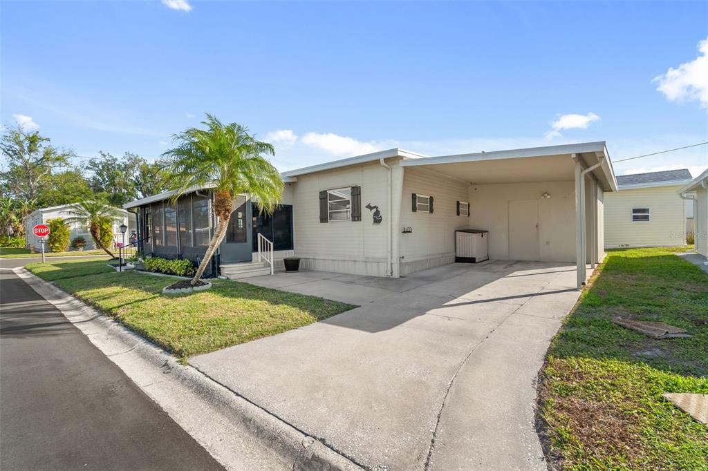 A single-story mobile home with a carport, a screened porch, and a concrete driveway — 2900 8TH AVENUE W UNIT 23, PALMETTO, FL