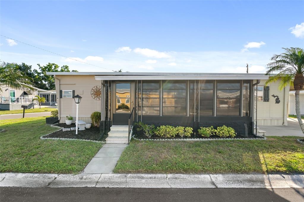 A single-story manufactured home with a screened-in front porch and beige siding — 2900 8TH AVENUE W UNIT 23, PALMETTO, FL