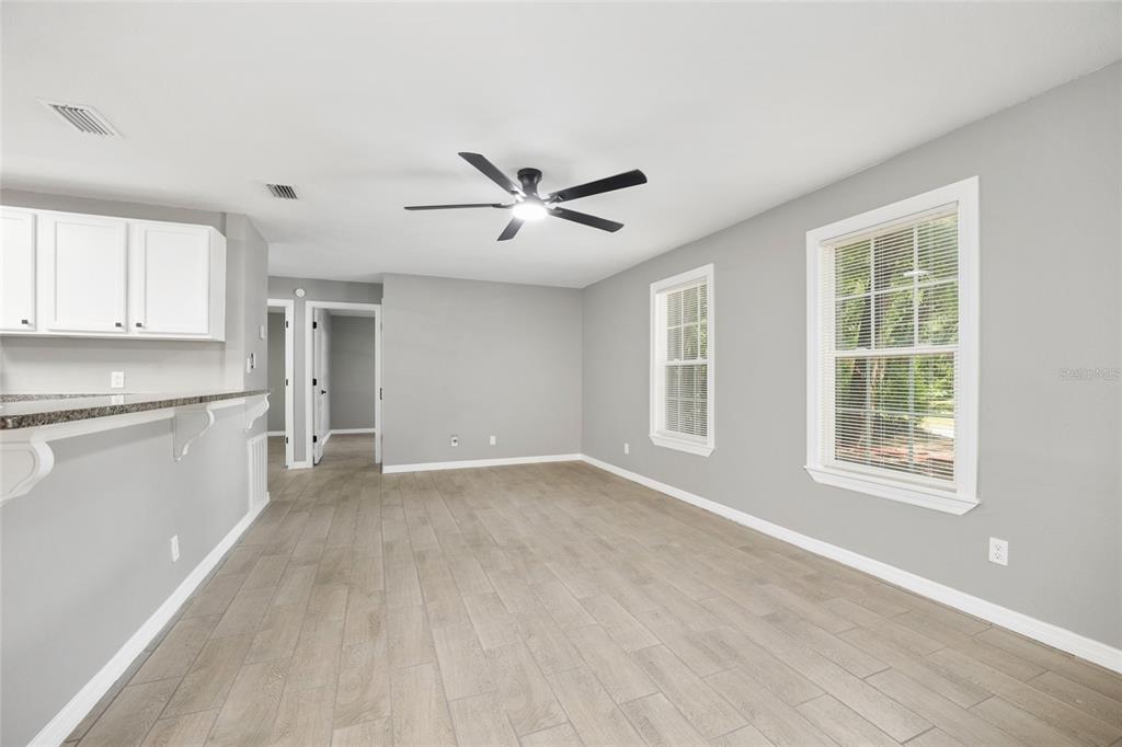 A living room with light gray walls, wood-look tile flooring, and a ceiling fan — 5805 NW 16TH STREET, OCALA, FL