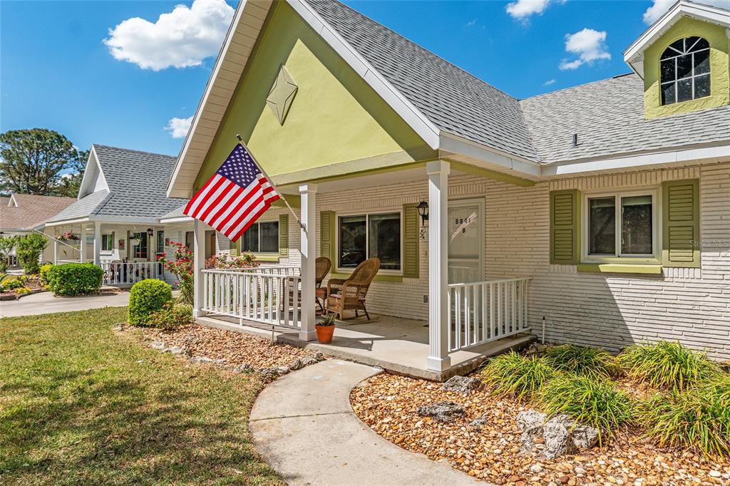 A single-story house with a white brick exterior, a front porch, and an American flag — 8841 SW 91ST STREET UNIT B, OCALA, FL