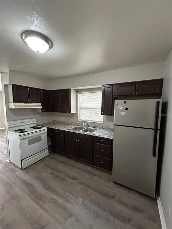 A kitchen features dark wood cabinets, stainless steel appliances, and light-colored countertops — 1484 32ND STREET NW, WINTER HAVEN, FL