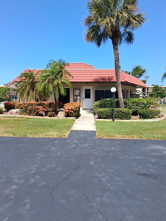 A single-story building with a red tile roof, palm trees, and a central white door — 12200 VONN ROAD UNIT 1304, LARGO, FL