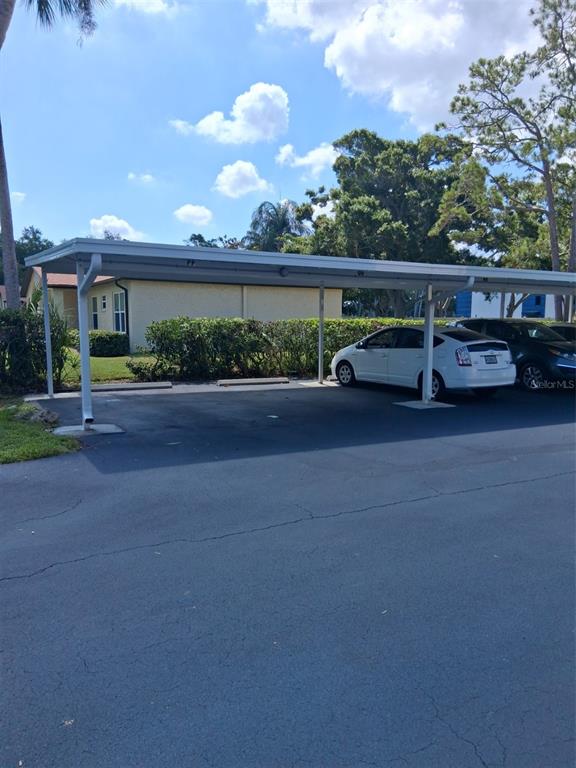 A covered parking area with a white metal structure sits above an asphalt lot — 12200 VONN ROAD UNIT 1304, LARGO, FL