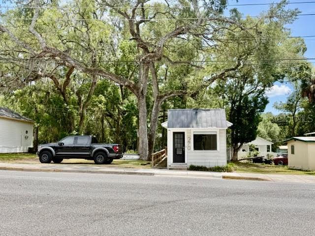 A black pickup truck is parked next to a small, white building under large trees — 270 N BROAD STREET, BROOKSVILLE, FL