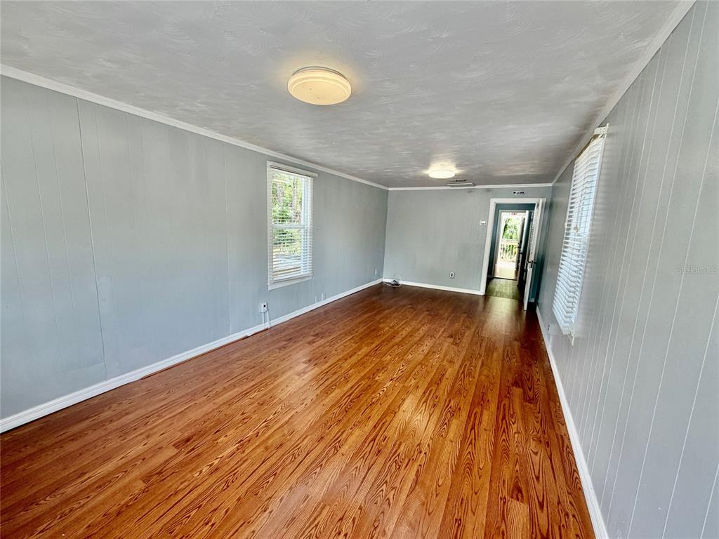 An empty room features light gray paneled walls, hardwood flooring, and two ceiling light fixtures — 270 N BROAD STREET, BROOKSVILLE, FL